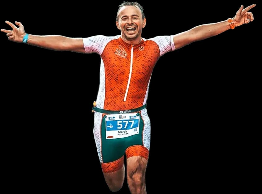 An 80/20 athlete celebrating at the finish line, arms raised.